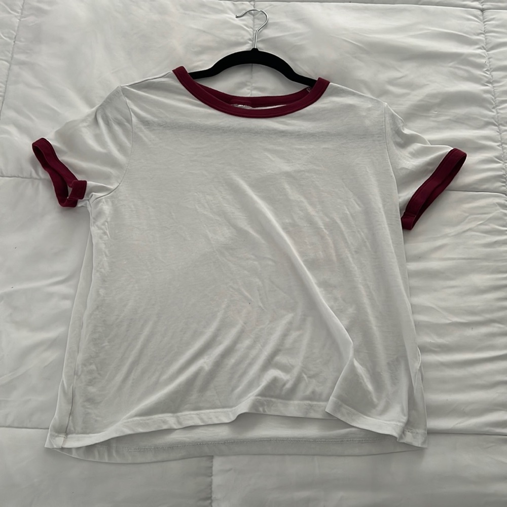 Medium, white, red trimmed t shirt with short sleeves.